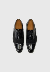 Black dress shoes with a pointed toe, featuring patent leather accent and suede upper. Designed with a textured pattern on the sides.