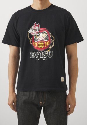T-shirt en coton noir avec un motif graphique d'un daruma et d'un renard, aux couleurs vives, accompagné du texte "EVISU EST. 1991." en blanc.