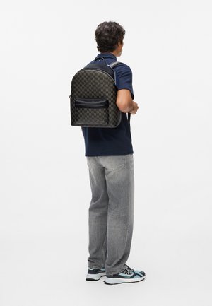 Sac à dos noir et marron à motif, de forme arrondie, avec des accents en cuir, une poche zippée à l'avant et des bretelles réglables.