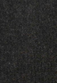 Tessuto nero strutturato con una trama grossa, che mostra un mix di fibre scure e chiare per profondità. Uniforme nel colore con una sensazione organica.