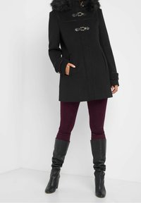 Svart ullkappa med konstgjord päls på huvan, toggelknäppningar och sidofickor. Matcher med burgundy leggings och knähöga svarta stövlar.