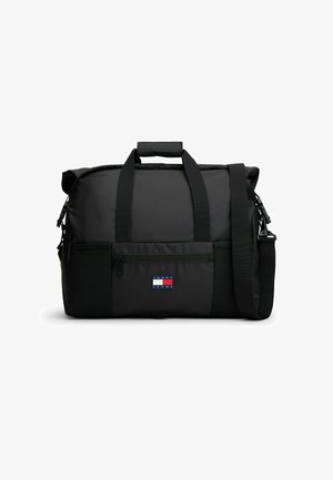 Zwarte Tommy Jeans duffeltas met dubbele handvatten, een voorvak met rits en een verstelbare schouderriem op een witte achtergrond.