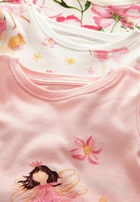 Magliette per bambini con scollo rotondo, una rosa con stampa di fata e fiori, l'altra bianca con motivi di ballerina e fiori.