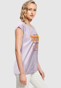 Light lavender t-shirt with a round neckline, short rolled sleeves, featuring a colorful graphic design with text on the front.