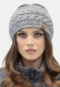 Diadema de punto gris con un patrón trenzado, que presenta una pequeña etiqueta de cuero. Textura suave y diseño ancho, adecuado para el clima frío.