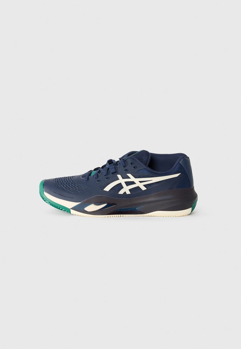 Chaussure de sport marine avec une tige texturée, logo blanc et accents verts sur le bout et la semelle extérieure. Comprend une semelle rembourrée pour le soutien.