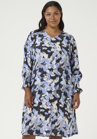 Vestido estampado floral en negro, azul y crema. Presenta un escote en V, mangas largas abullonadas con puños fruncidos y un corte holgado.