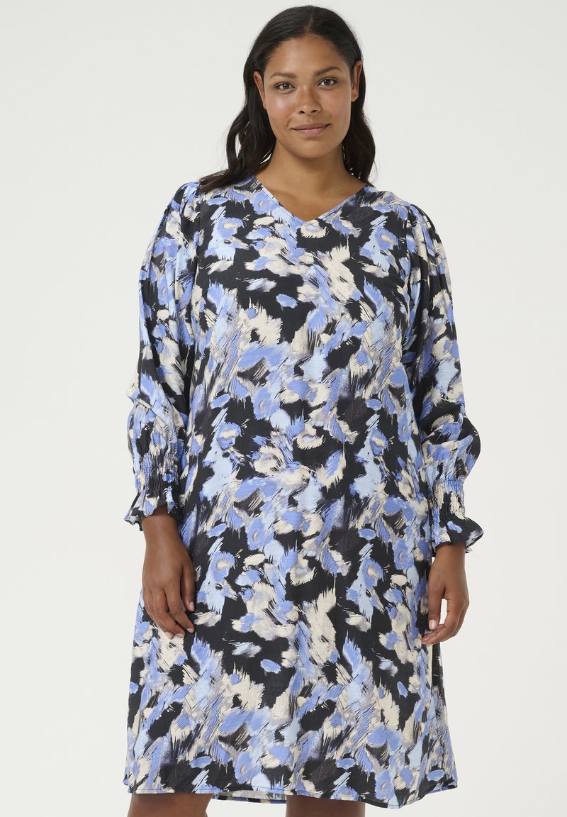 Vestido estampado floral en negro, azul y crema. Presenta un escote en V, mangas largas abullonadas con puños fruncidos y un corte holgado.