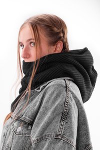 Black knitted scarf with a textured design, worn over a gray denim jacket. The scarf features a large, hoods-like shape and folds.