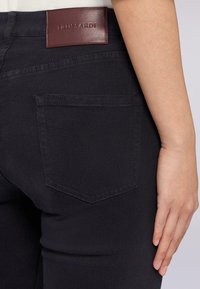 Černé denimové džíny s přiléhavým střihem, viditelnou zadní kapsou a burgundskou koženou visačkou s embosovaným logem "TRUSSARDI".