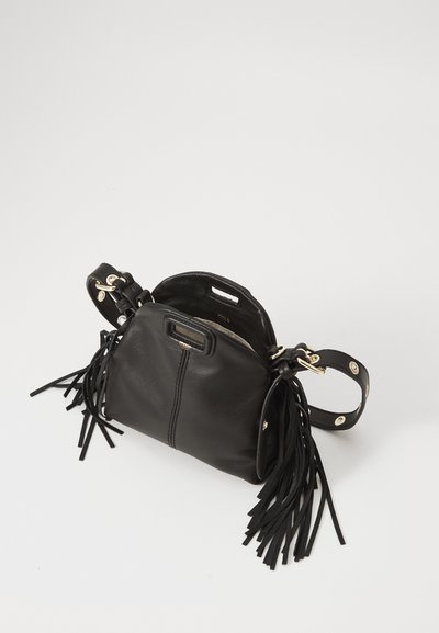 Sac à main en cuir noir avec des accents de franges, une forme arrondie, du matériel doré et une bandoulière amovible. L'intérieur est visible, avec une doublure claire.