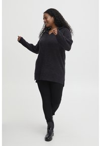 Tunique sombre et texturée avec capuche, manches longues et coupe décontractée, associée à des leggings noirs et des bottines. Design simple, sans motifs.