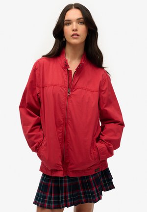 Rød letvægtsjakke med lynlås foran, stående krave og sidelommer. Har en glat tekstur og elastiske manchetter.