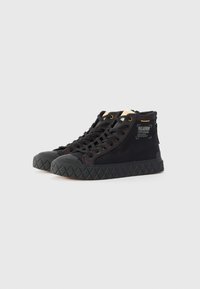 Baskets montantes noires avec une semelle en caoutchouc texturé, un upper en tissu, des œillets dorés et un patch logo sur le côté.
