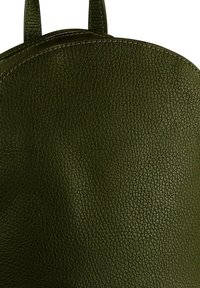 Donkergroene leren rugzak met textuur, afgeronde bovenkant en zichtbare gestikte bandjes, tegen een witte achtergrond.