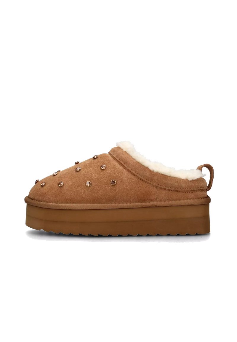Pantofole in camoscio marrone con fodera in pelliccia sintetica color crema, suola spessa e borchie decorative color oro rosa sulla superficie superiore. Presenta una linguetta posteriore.