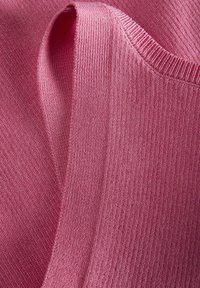 Tekstūruota rožinė megzta medžiaga su įbrėžimų kraštais, turinti švelnų, lyg�ų paviršių ir vienodą spalvą visame plote.