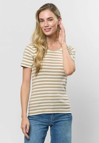 Bežs un balts svītrots īsām piedurknēm tops ar ribotu tekstūru, ar apaļu kakla izgriezumu. Apvienots ar ziliem džinsiem.