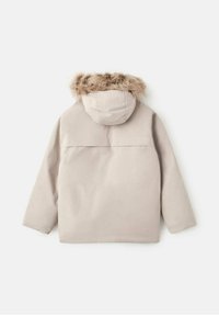Chaqueta de invierno color beige claro con capucha forrada de piel, corte recto y textura suave. Presenta un diseño minimalista sin cierres visibles.