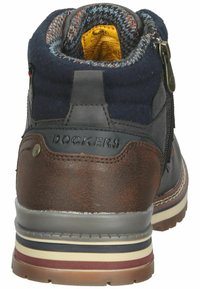 Braune und marineblaue Mid-Top-Stiefel mit einem Obermaterial aus Leder und Textil, Reißverschluss und einer strukturierten Gummisohle mit mehrfarbigen Streifen.