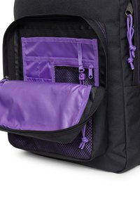 Czarny plecak z fioletowym wnętrzem, wyposażony w wiele kieszeni, sekcje z siateczki i zamki błyskawiczne. Gładka tkanina i trwała konstrukcja.