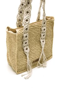 Bolso de paja trenzada con intrincados mangos de macramé blancos y cuentas de madera decorativas, que presenta una forma rectangular y una superficie texturizada.