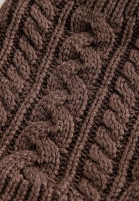 Braun gestrickter Stoff mit einem Kabelmuster, das dicke, strukturierte Garne und erhöhte Zöpfe aufweist, die vertikal verlaufen. Weiches und warmes Aussehen.