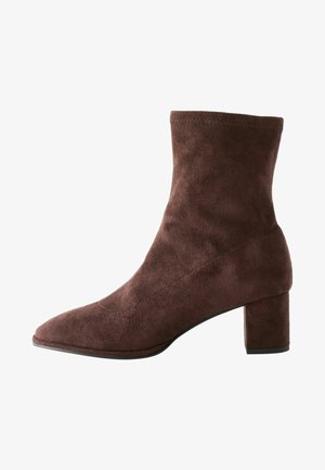Bottine en suède marron à bout pointu et à talon bloc. Caractérisée par une texture lisse et un design minimaliste.