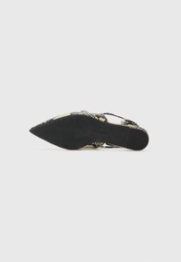Zapato de punta afilada con un upper de patrón de reptil en beige y marrón, presentando una suela negra y un diseño de correa ajustable.