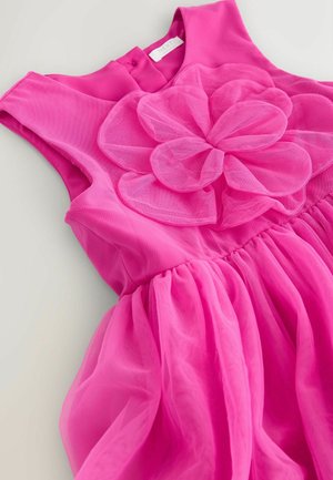 Roze mouwloze jurk gemaakt van zachte stof met een geplooide rok en een grote tule bloemvormige detail bij het lijfje. Sluiting met knopen aan de achterkant.