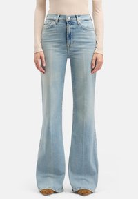 Jean évasé bleu clair en denim, avec une taille haute, cinq poches, un léger effet délavé, et une finition propre à l'ourlet.