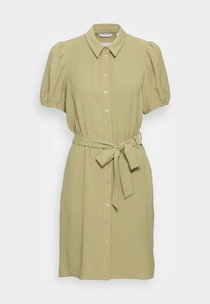 Robe chemise vert olive clair avec des manches courtes bouffantes, un devant à boutons, un col pointu et une ceinture en tissu nouée à la taille.