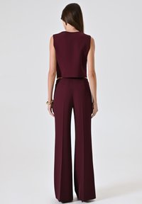 Completo bordeaux composto da un top senza maniche e pantaloni a gamba larga in vita alta, realizzato in tessuto liscio e testurizzato.