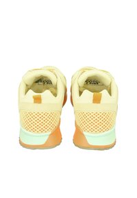 Gelbe Laufschuhe mit Netzpaneelen, kontrastierenden orangen Akzenten und grünen Sohlen. Verfügt über eine strukturierte Oberfläche und eine Schlaufe an der Ferse.