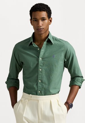 Green button-up shirt with long sleeves, featuring a small purple logo on the chest. The fabric appears soft with a relaxed fit.