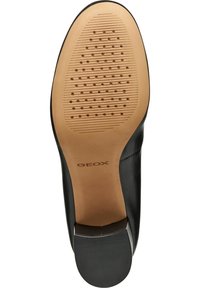 Svart läderskoled med mönstrade spår och små ventilationshål; har en slät tanfärgad fotbädd och en lätt klack.