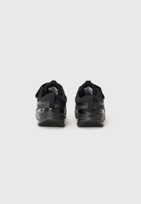 Chaussures de sport noires au design épuré, avec une tige en maille texturée et des accents brillants. Semelle en caoutchouc avec un motif pour une meilleure adhérence.