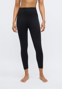 Schwarze, hoch taillierte Leggings aus glattem, dehnbarem Material. Schlanke Passform, knöchellang, mit bequemem breitem Bund.