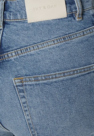 Μπλε τζιν παντελόνι με ψηλή μέση, διαθέτει πίσω τσέπη και διακριτές ραφές. Η ετικέτα γράφει "IVY & OAK."