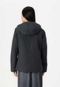 Černá péřová bunda s kapucí, s hladkým povrchem a mírně zúženým designem. Zadní strana ukazuje čistou, minimalistickou siluetu.