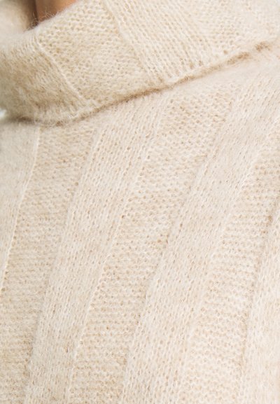 Suéter de gola alta de cor creme, feito de um tecido suave e texturizado. Apresenta padrões verticais em malha e um colarinho alto e aconchegante.