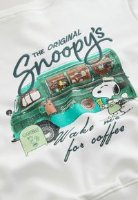 Bílá mikina s grafikou zeleného vintage kávového vozu a postavami, modrý nápis „Snoopy's Wake me for coffee“.