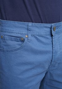 Blå bomullsshorts med klassisk femficksdesign, metalldetaljer och en mjuk textur.