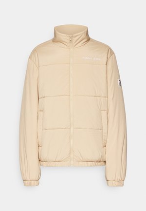 Beżowa puchowa kurtka z wysokim kołnierzem, zamkiem błyskawicznym z przodu, elastycznymi mankietami i bocznymi kieszeniami. Posiada logo "TOMMY JEANS" na piersi oraz metkę z logo na rękawie.
