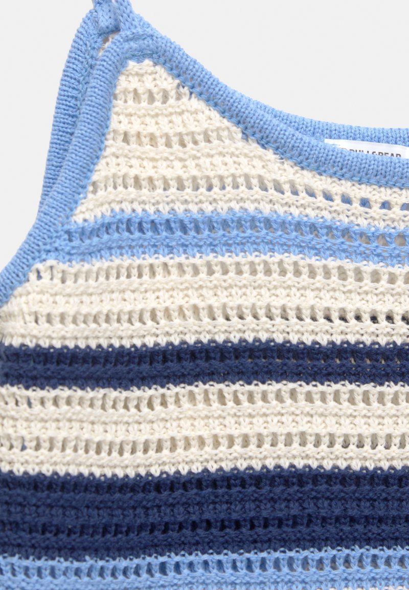 Top en crochet avec un motif rayé multicolore dans des nuances de blanc, marine et bleu clair, avec un design en dentelle texturée.