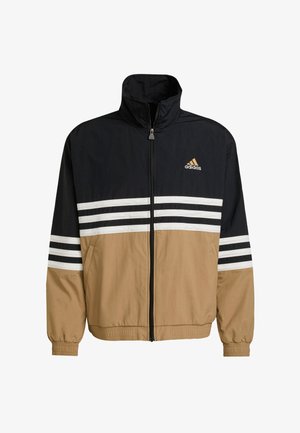 Sort, tan og hvid vindjakke med høj krave, fuld lynlås foran, hvide striber på ærmerne og et adidas-logo på brystet.