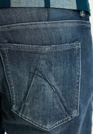 Dunkelblaue Denim-Jeans mit einem verblassten Effekt. Auffälliges dreieckiges Taschendesign und helle Nähdetails. Leder-Patch am Bund.