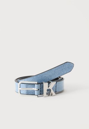 Lyseblåt denim bælte rullet sammen med en sølv spænde og et sølv K-detail på en hvid baggrund.