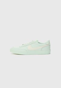 Baskets vert clair avec une tige texturée, dotées d'un swoosh couleur crème, de lacets plats et d'une semelle en caoutchouc. Dessus arrondi et design à profil bas.