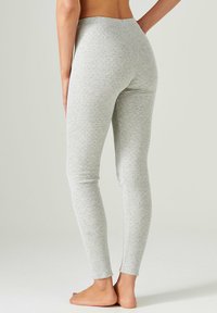 Leggings grigi realizzati in un morbido tessuto testurizzato, con un design aderente e una cintura liscia. La superficie presenta un motivo sottile.